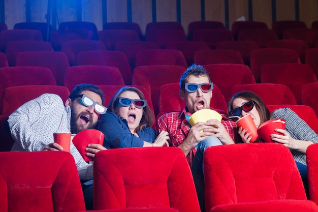 A variety of human emotions of friends holding a cola and popcorn in the cinema.