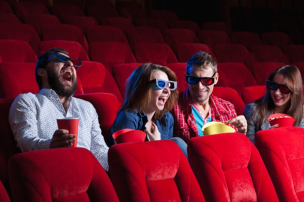 A variety of human emotions of friends holding a cola and popcorn in the cinema.