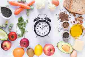 Free photo variety of ingredients with alarm clock arranged against isolated on white background