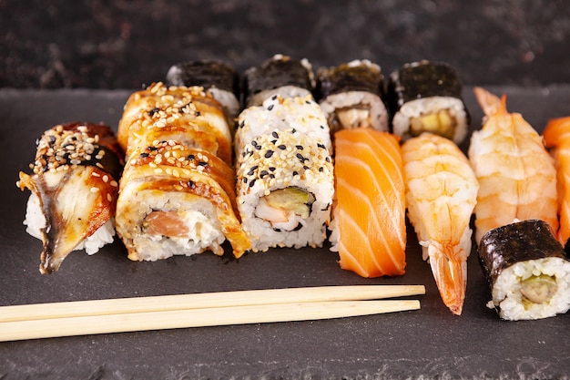 Variety mix of sushi rolls on black background in studio photo