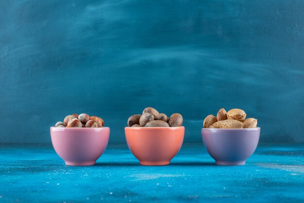 Разнообразие орехов в мисках на синей поверхности