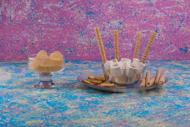 Variety of pastires in glass cup and platter on pink background