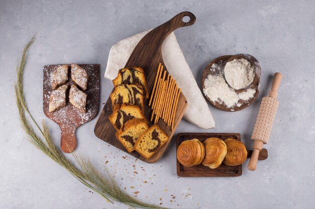 Variety of pastries and crackers on a wooden board, top view