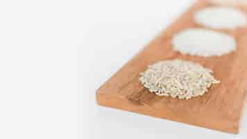 Free photo variety of rice on wooden tray over white background