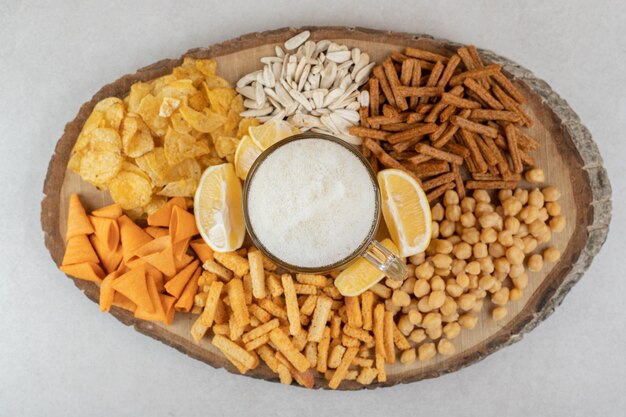 Variety of snacks and glass of beer on wooden piece