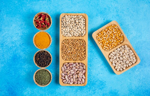 Variety of spices and raw beans on blue surface