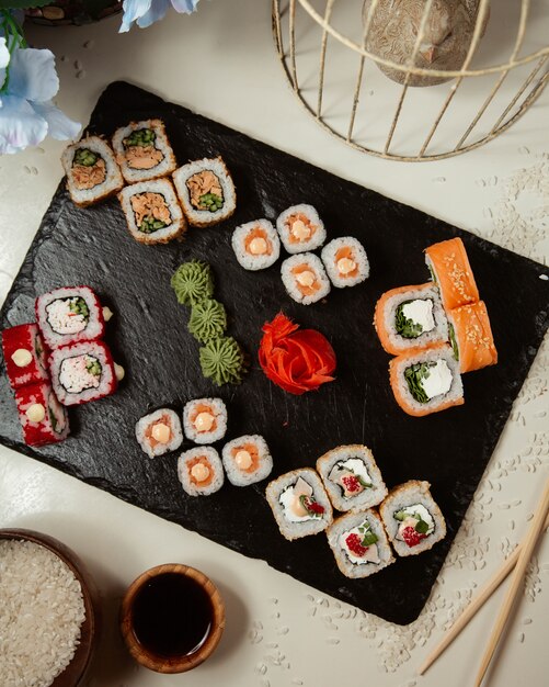 Variety of sushi rolls on a black board.