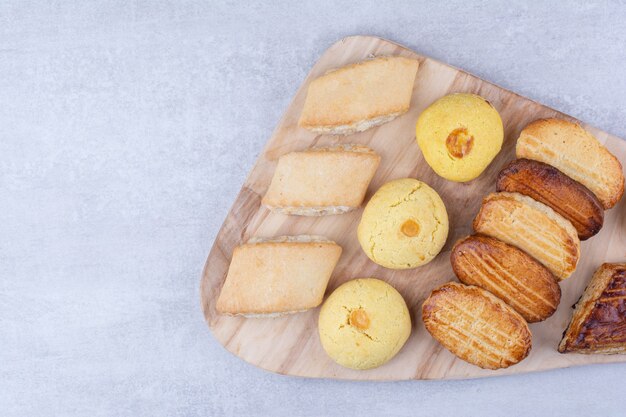 Variety of tasty cookies on wooden board.