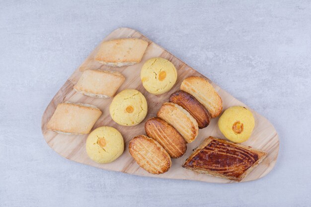 Variety of tasty cookies on wooden board.