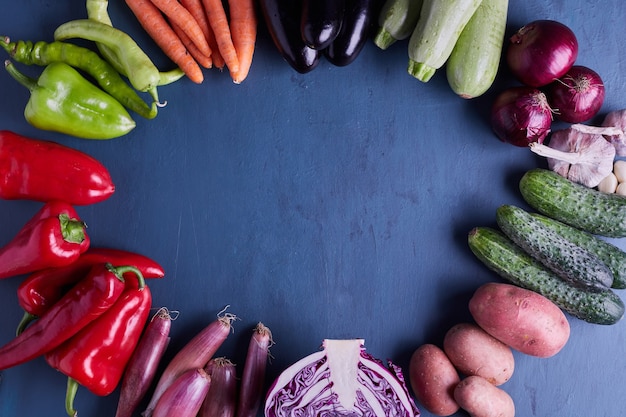 Variety of vegetables in a circle on blue table.