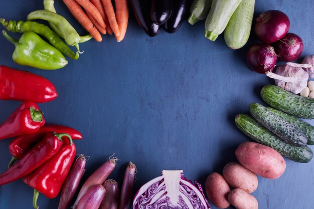 Variety of vegetables in a circle on blue table.