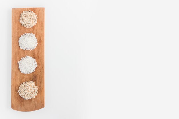 Variety of white and brown rice on wooden tray