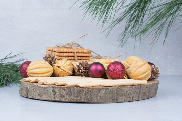 Различное печенье и рождественские украшения на деревянной доске.