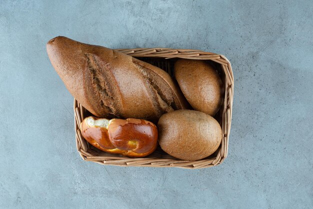 Различный хлеб и выпечка в деревянной корзине.