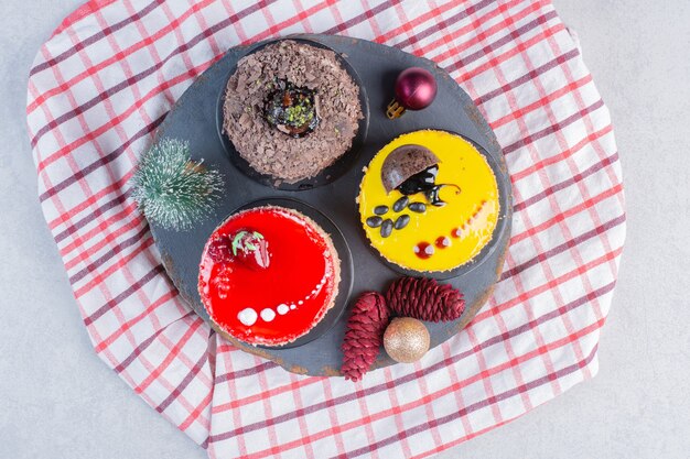 Various cakes on dark board with Christmas ornaments. 