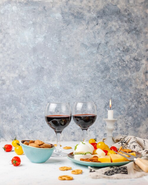 Various cheese and cheese plate on light table with different nuts and fruits and glass of wine