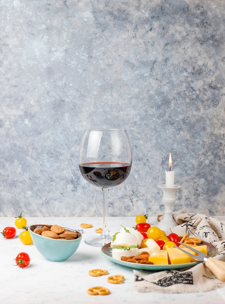 Various cheese and cheese plate on light table with different nuts and fruits and glass of wine