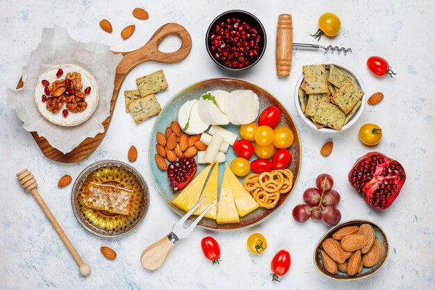 Various cheese and cheese plate on light table with different nuts and fruits