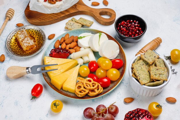 Various cheese and cheese plate on light table with different nuts and fruits