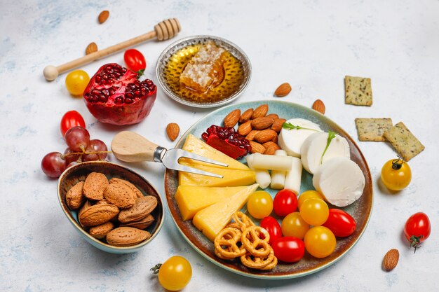 Various cheese and cheese plate on light table with different nuts and fruits