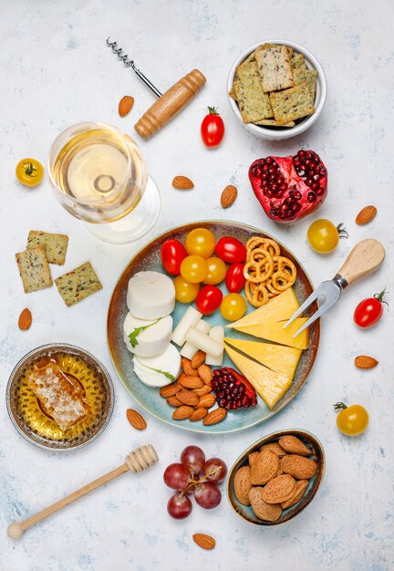 Various cheese and cheese plate on light table with different nuts and fruits