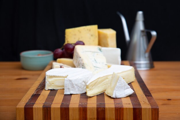 Various cheeses laying on wooden board