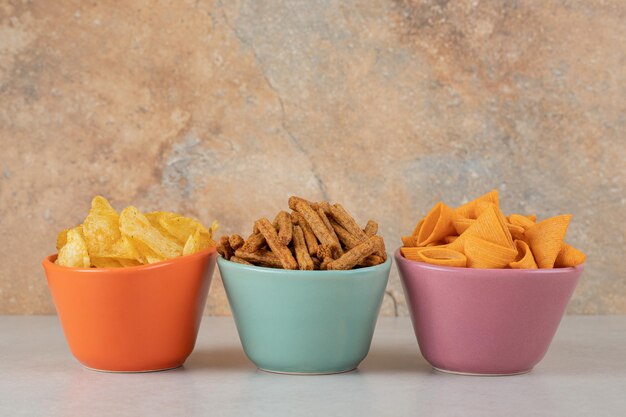 Various chips and crackers in colorful bowls