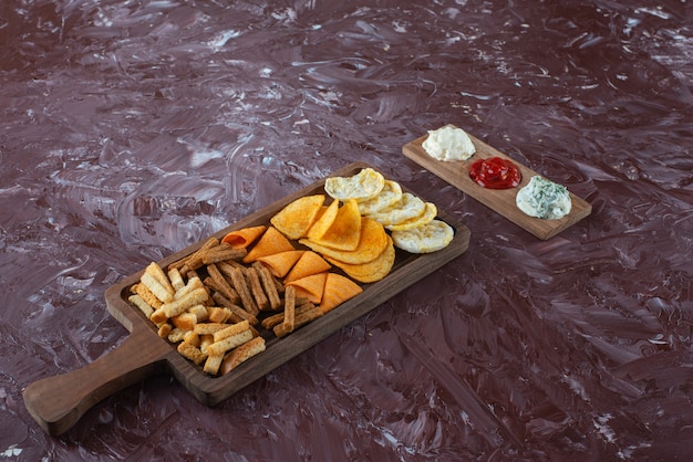 Free photo various chips on serving board with sauce , on the marble table.