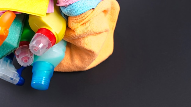 Various cleaning products in basket over black surface