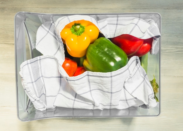 Various colorful bell peppers wrapped with napkin in transparent container