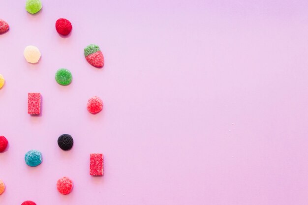 ピンクの壁紙に様々なカラフルなゼリー砂糖キャンデー
