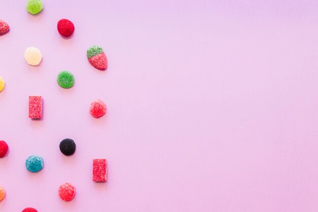 Various colorful jelly sugar candies on pink wallpaper