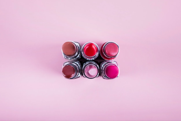 Various colorful lipsticks on pink background