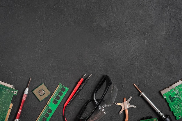 Various computer parts; digital multimeter and safety glasses on black background