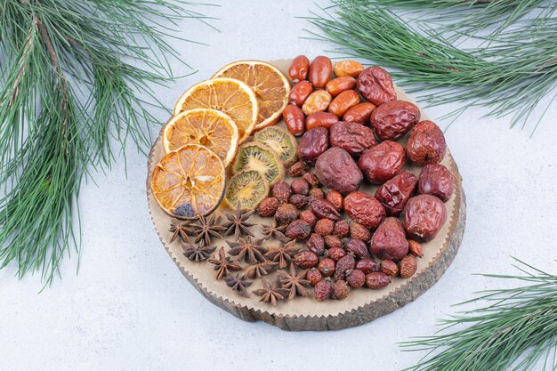 Various dried fruits and cloves on wooden piece. 