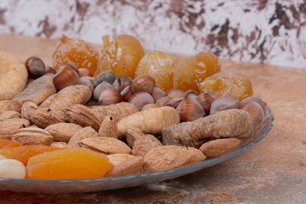 Various dried fruits and nuts on glass plate.