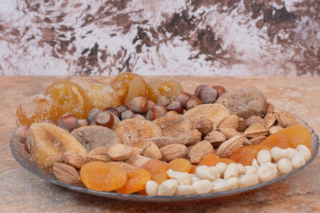 Various dried fruits and nuts on glass plate.