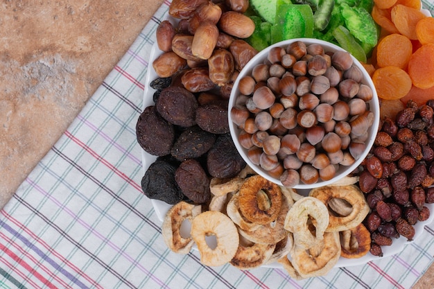 Various dried fruits and nuts on white plate.