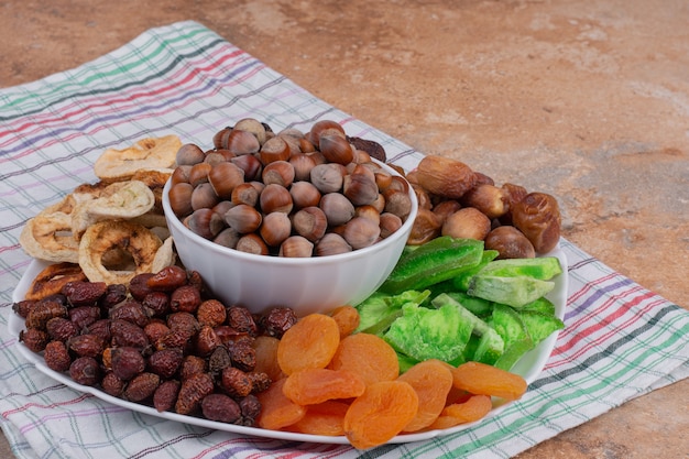 Various dried fruits and nuts on white plate.