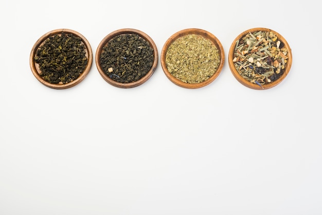 Various dried meadow herbs tea on wooden circular plate against white background