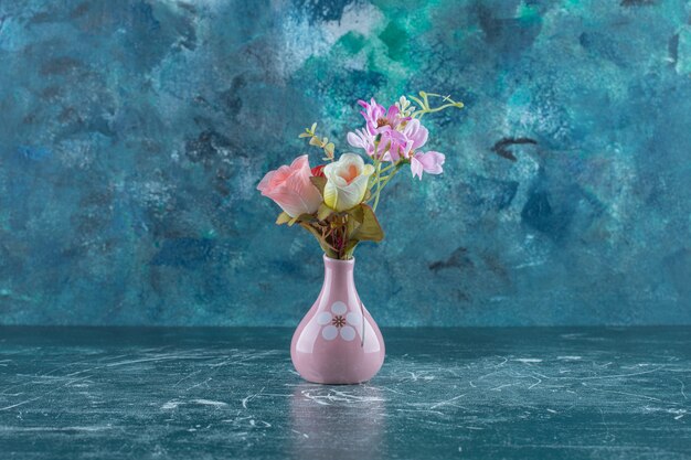 Various flowers in a vase , on the blue table. 