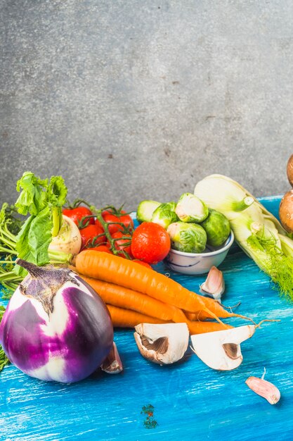 Various fresh organic vegetables on blue wooden surface