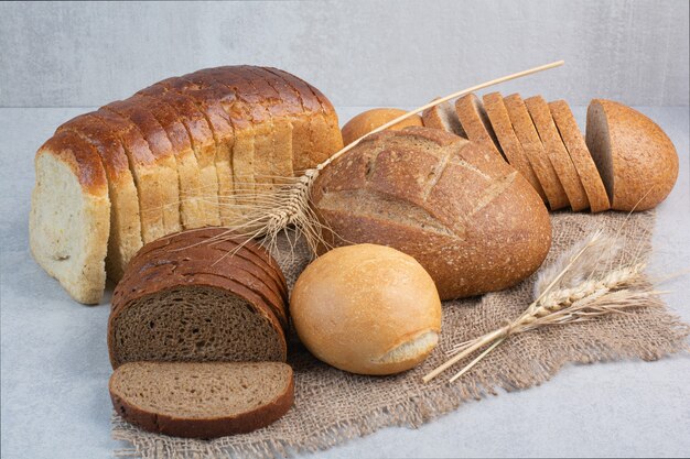 Различный домашний хлеб на мешковине с пшеницей. Фото высокого качества