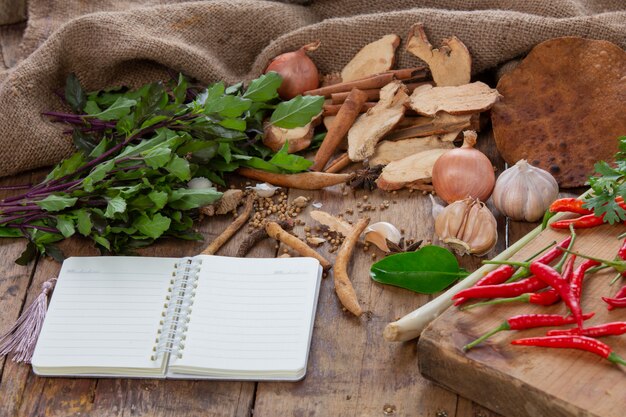 Various ingredients used to make Asian food are placed along with the notebooks on the wooden table.