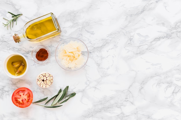 Various ingredients with oil on white marble background