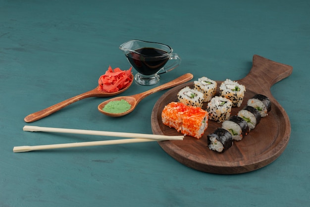 青いテーブルに生姜の酢漬け、わさび、醤油を添えた各種巻き寿司。