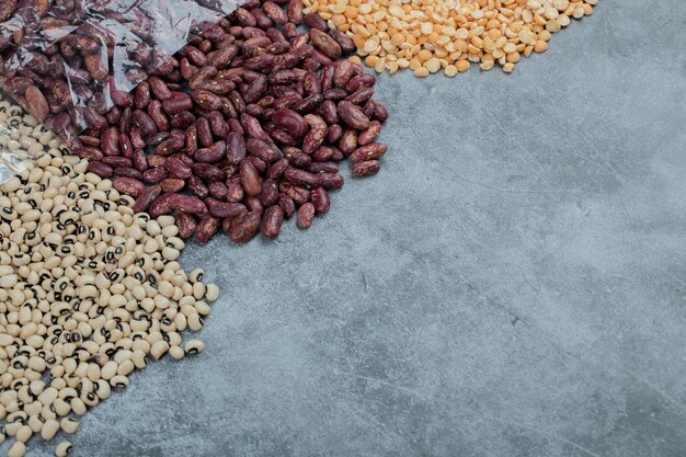 Various kinds of uncooked beans on marble surface.