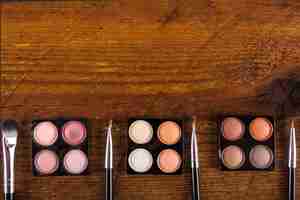 Free photo various makeup brushes and colorful eye shadow powders on wooden backdrop