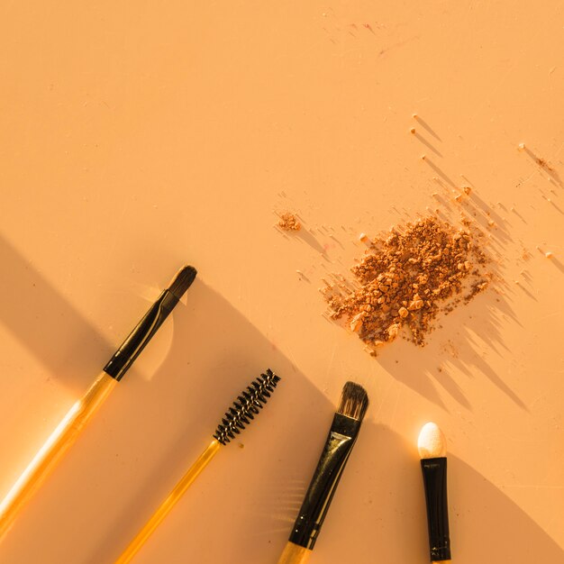 Various makeup brushes with face powder on color backdrop