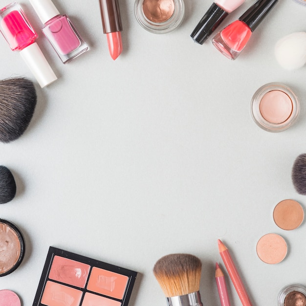 Various makeup products forming circular shape on white backdrop